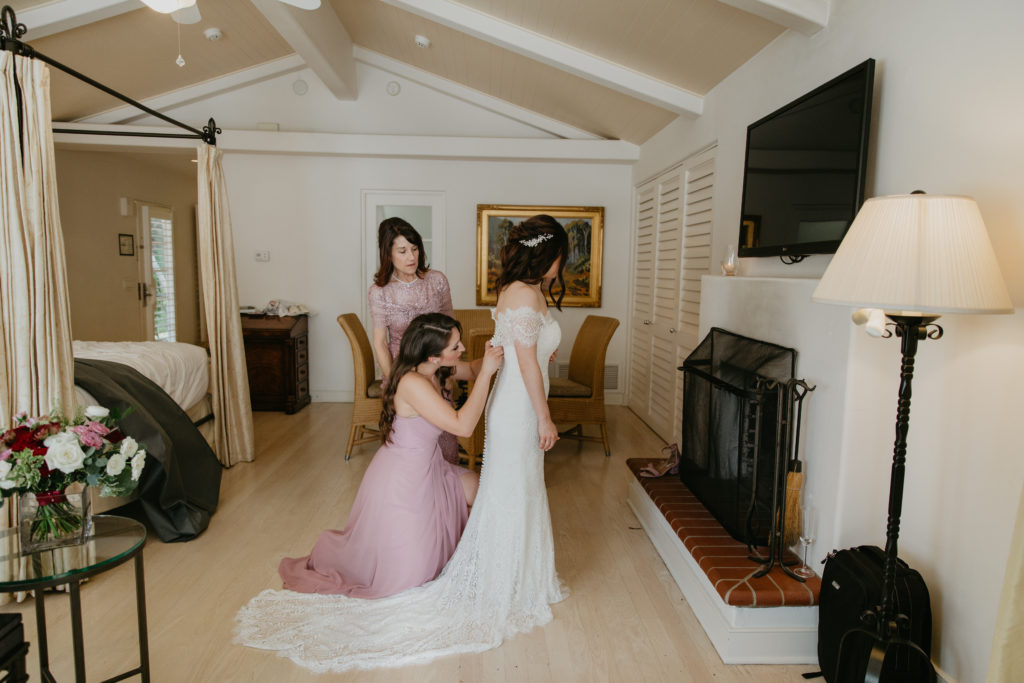 A music festival themed wedding at The Inn at Rancho Santa Fe, bride getting into wedding dress