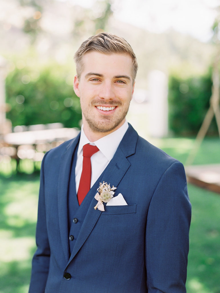 A colorful and vibrant wedding at Triunfo Creek Vineyards, groom in navy suit with red tie