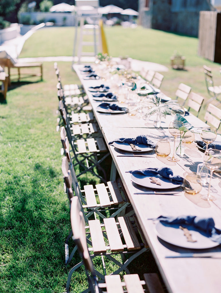 A California-cool rehearsal dinner at Calamigos Ranch, natural farm table with blue napkins and drink ware
