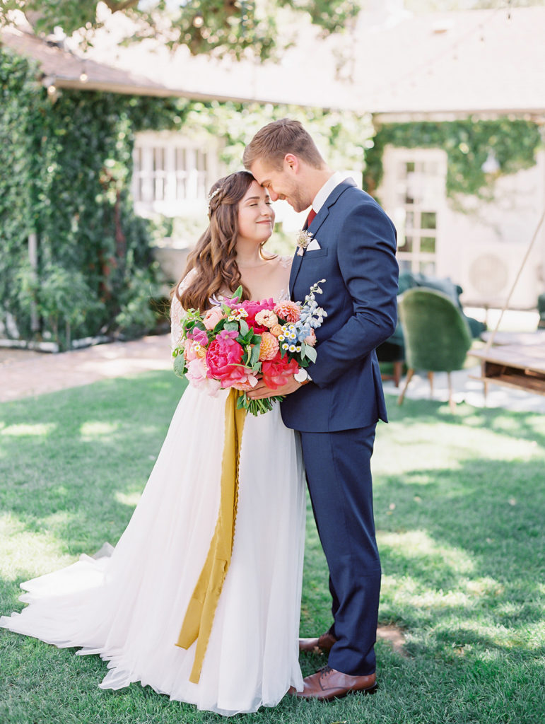 A colorful and vibrant wedding at Triunfo Creek Vineyards, bride and groom portrait shot, bright and colorful bridal bouquet with yellow ribbon