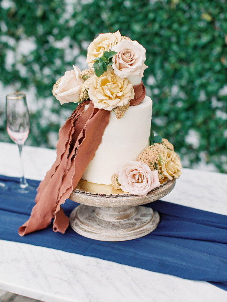 A colorful and vibrant wedding at Triunfo Creek Vineyards, wedding cake with orange ribbon