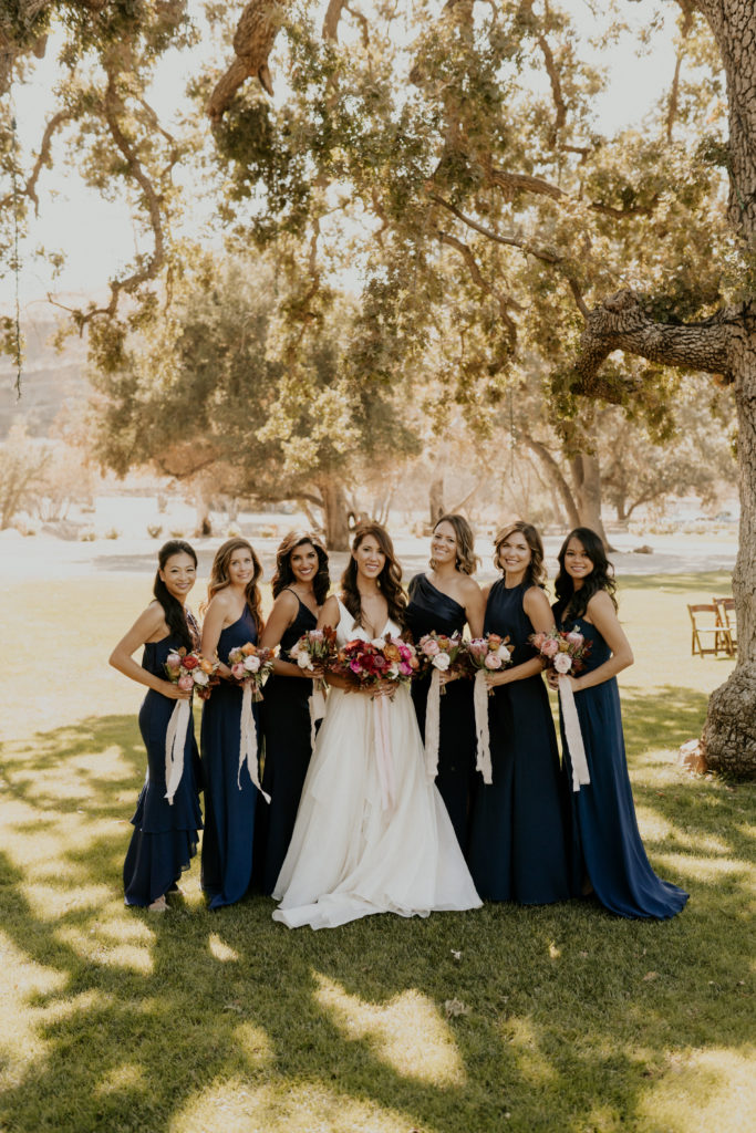 A whimsical wedding at Triunfo Creek Vineyards, bride with bridesmaids in navy blue dresses and pink bouquets