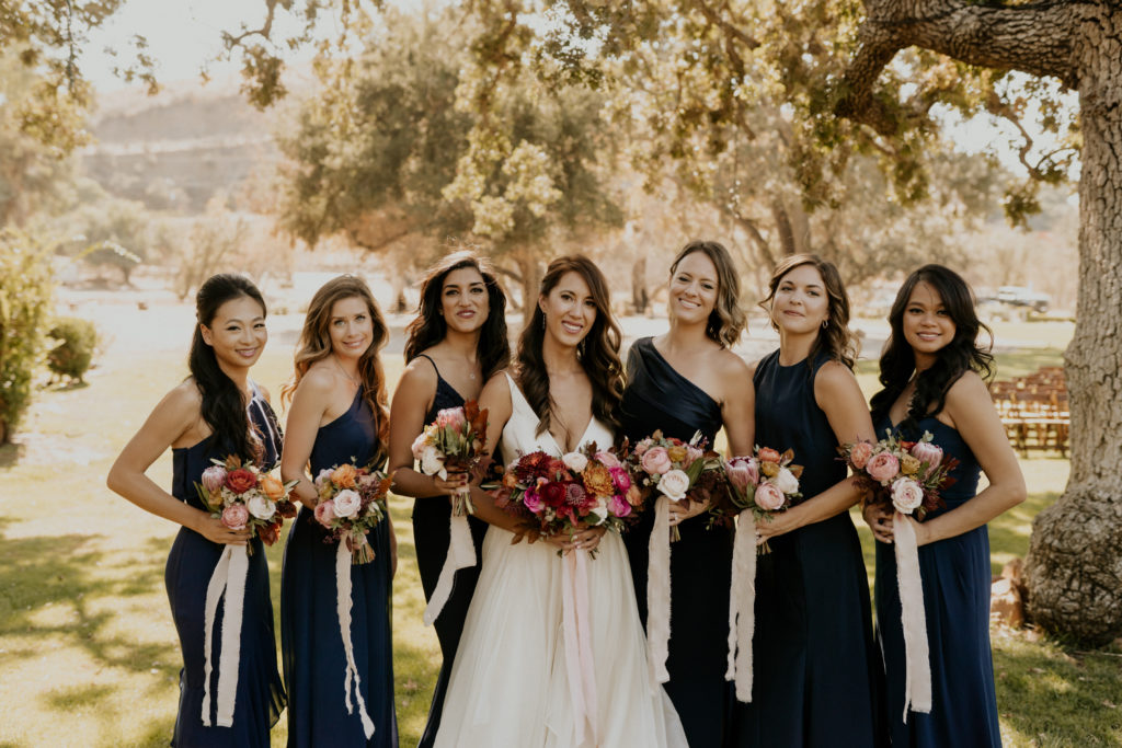 A whimsical wedding at Triunfo Creek Vineyards, bride and bridesmaids in navy blue dresses with pink bouquets