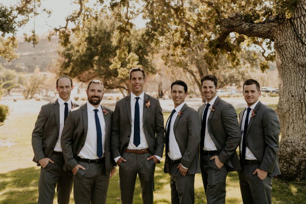 A whimsical wedding at Triunfo Creek Vineyards, groom and groomsmen in grey suits with navy blue ties