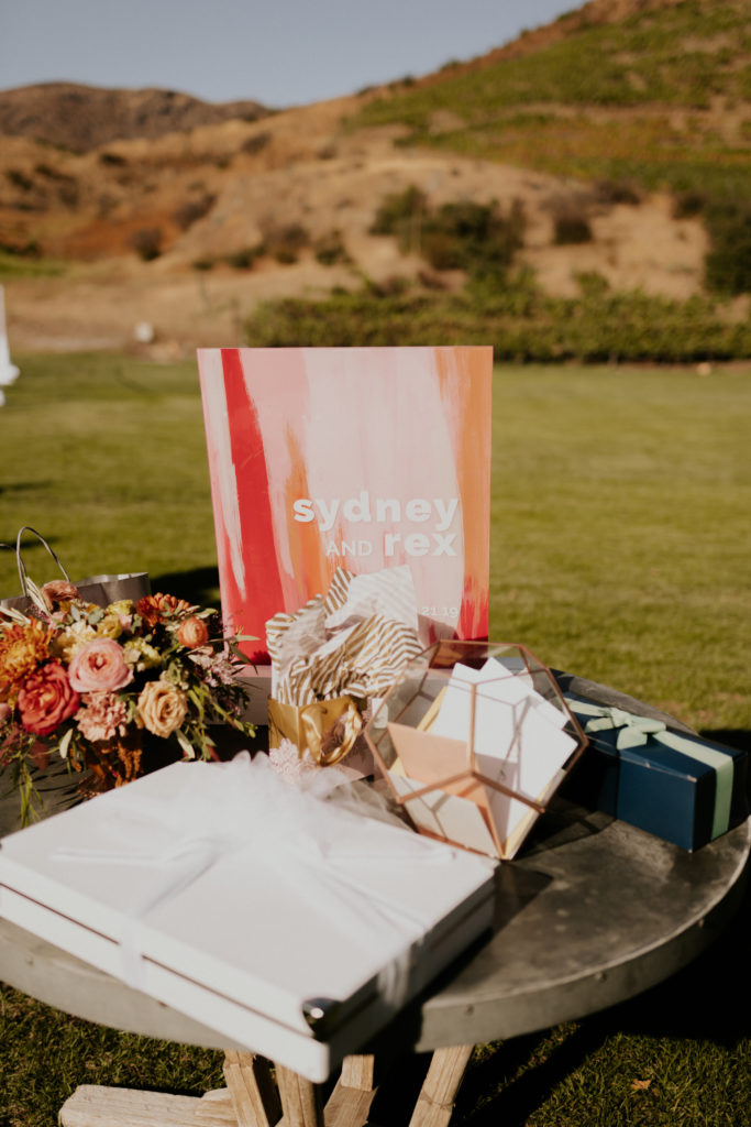 A whimsical wedding at Triunfo Creek Vineyards, acrylic welcome table sign with pink and orange paint