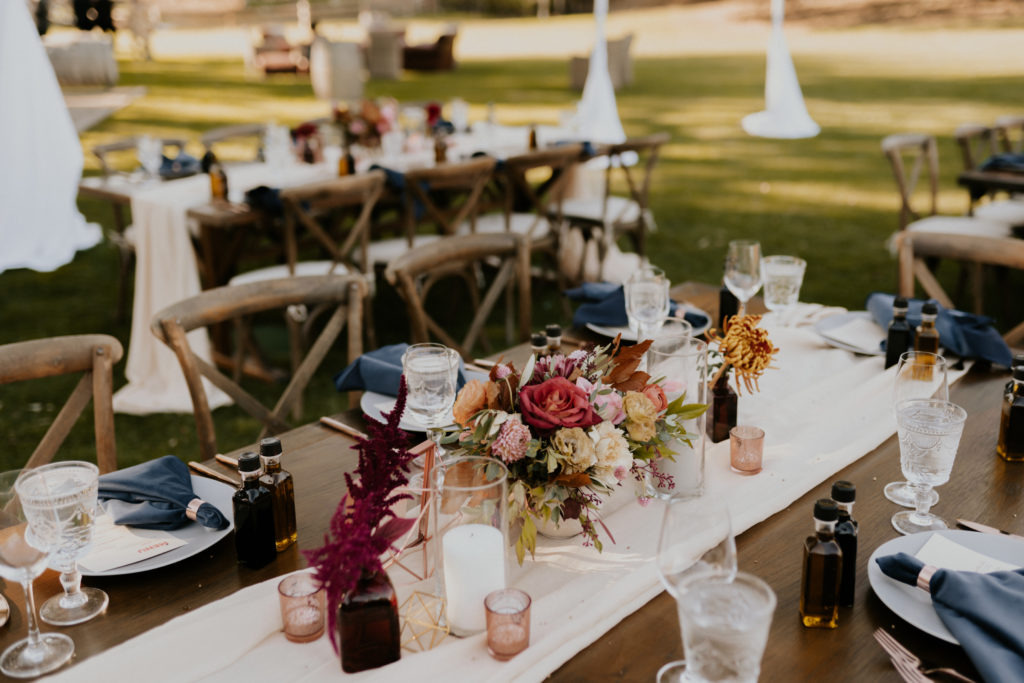 A whimsical wedding reception at Triunfo Creek Vineyards, farm table with pink and orange floral centerpiece