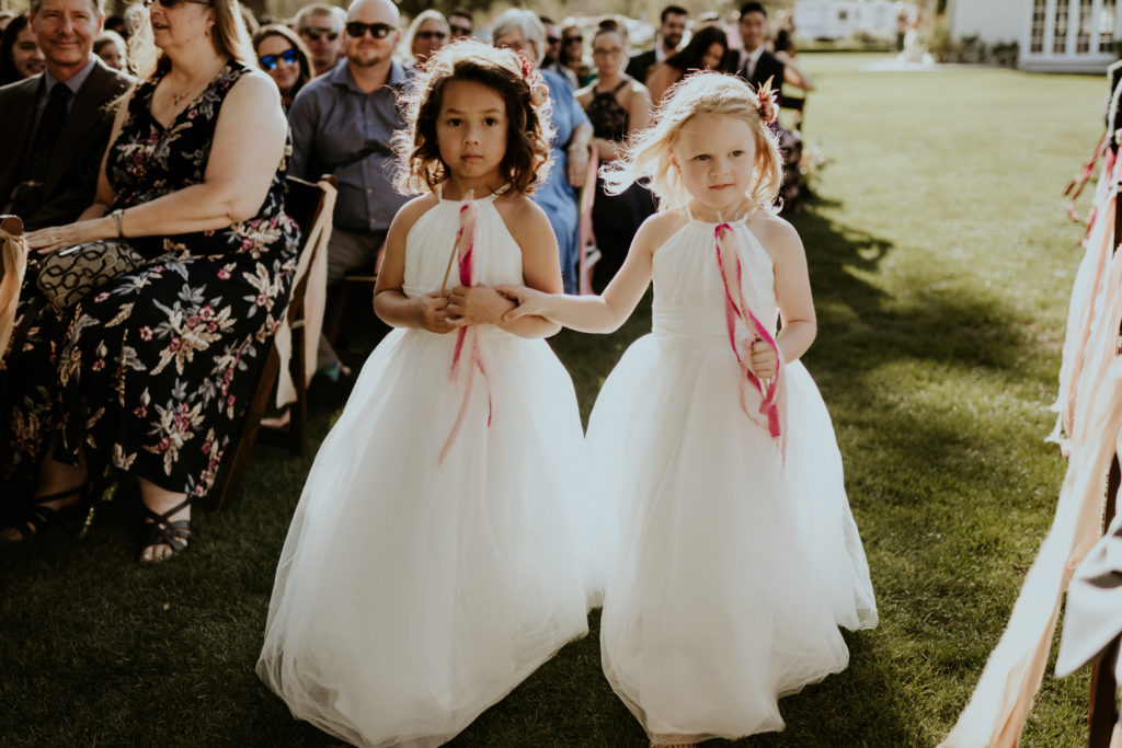 A whimsical wedding ceremony at Triunfo Creek Vineyards, flower girls with flower wands