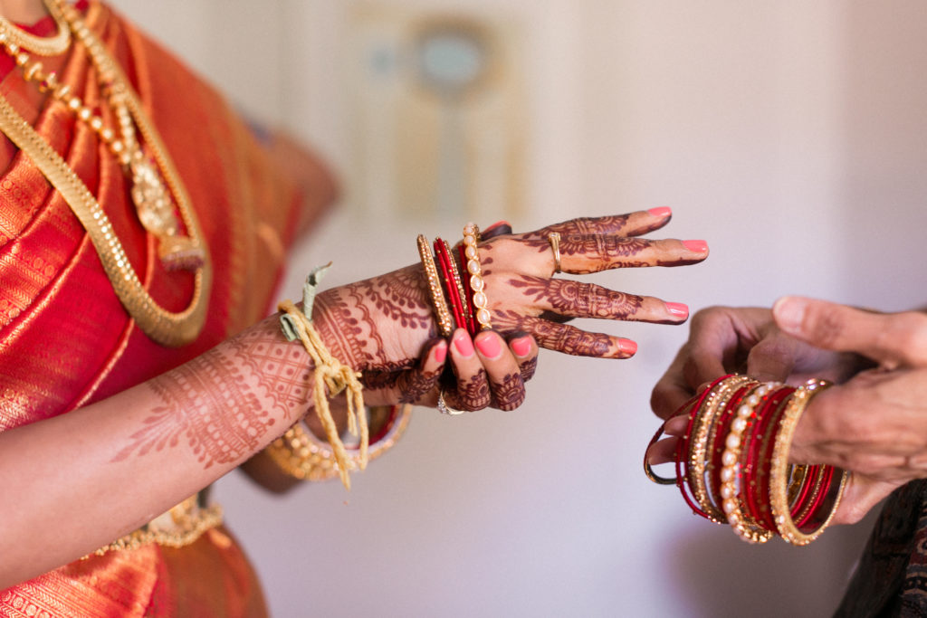 red bridal bangles being placed on bride getting ready for her wedding day