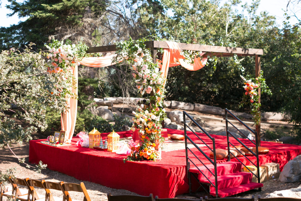 wedding at the Environmental Nature Center, ceremony with stage wrapped in red fabric and wooden mandap in coral drapery and flowers
