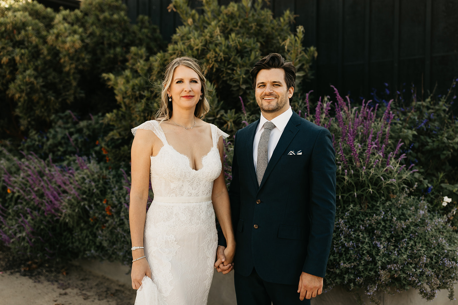 bride in lace dress with groom in dark blue suit portrait shot at Roblar Winery
