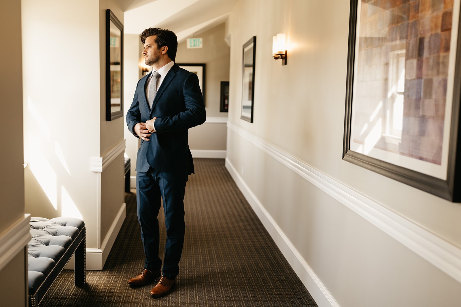 groom in dark blue suit with brown shoes and grey tie getting ready for his wedding day