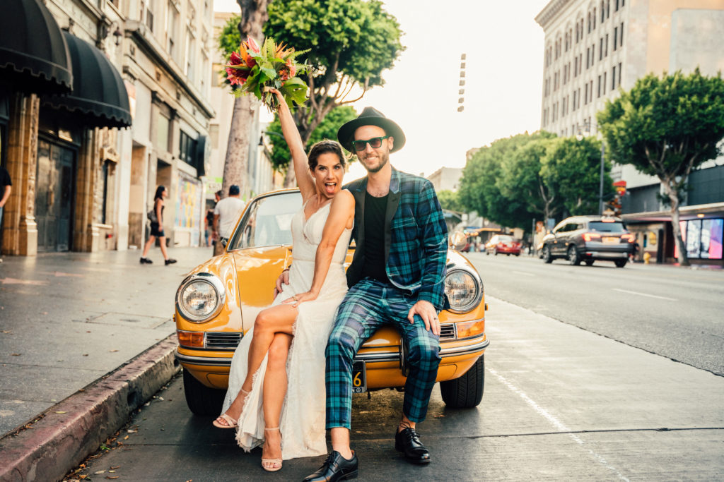 bride and groom arrive for rock inspired wedding in yellow vintage car