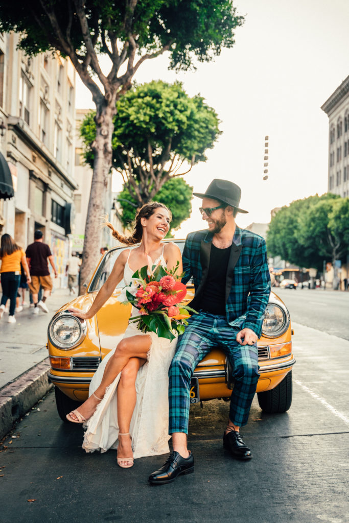 bride and groom arrive for rock inspired wedding in yellow vintage car