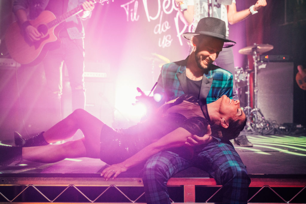 bride and groom pose on stage for rock inspired wedding