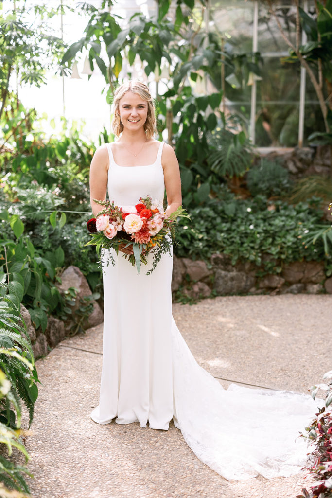 bride with short blond hair holding brightly colored bridal bouquet