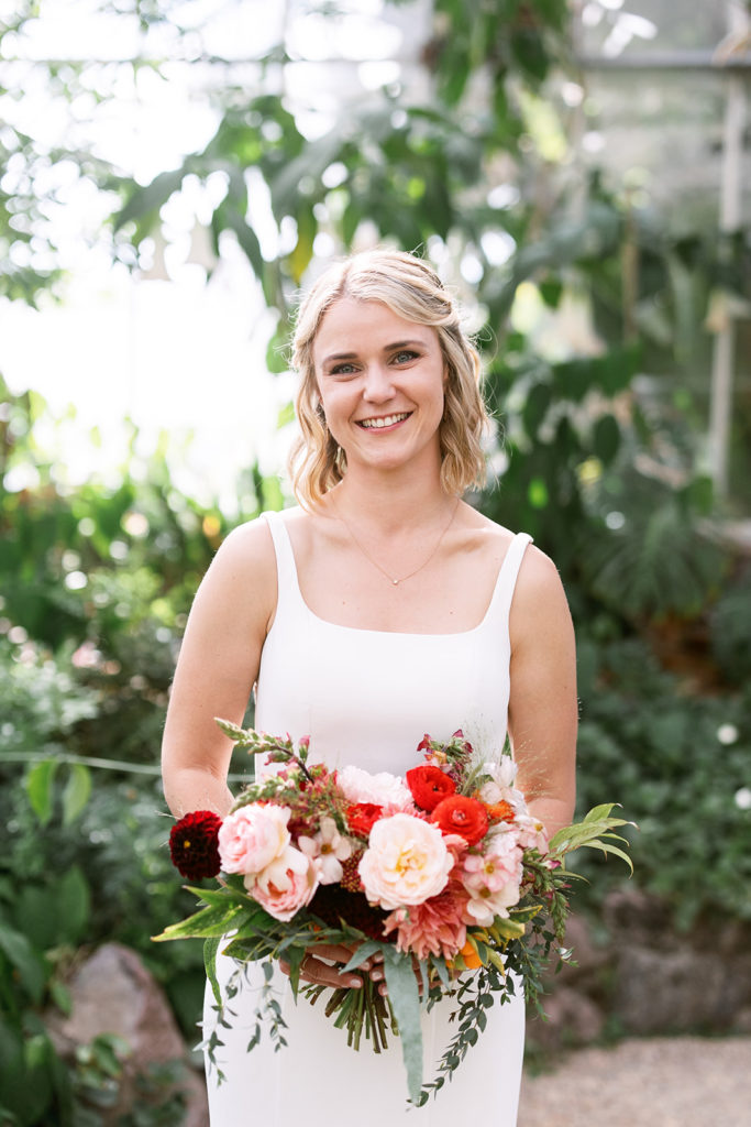 bride with short blond hair holding brightly colored bridal bouquet