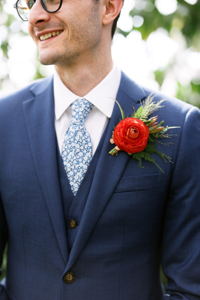 groom in blue suit with red boutonniere 