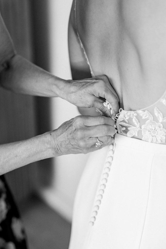 mother of bride buttoning lace back of daughter's wedding dress