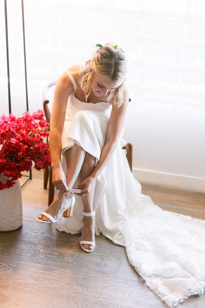 bride putting on white bridal shoes