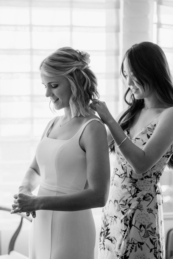 friend of bride putting jewelry on bride