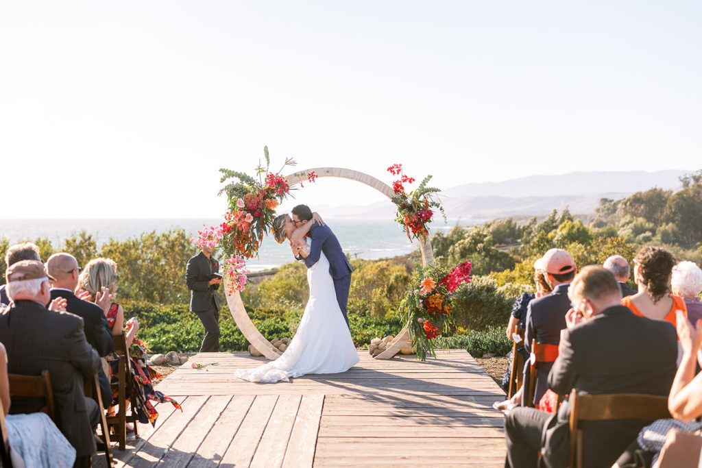 bride and groom first kiss during wedding ceremony at Dos Pueblos Orchid Farm