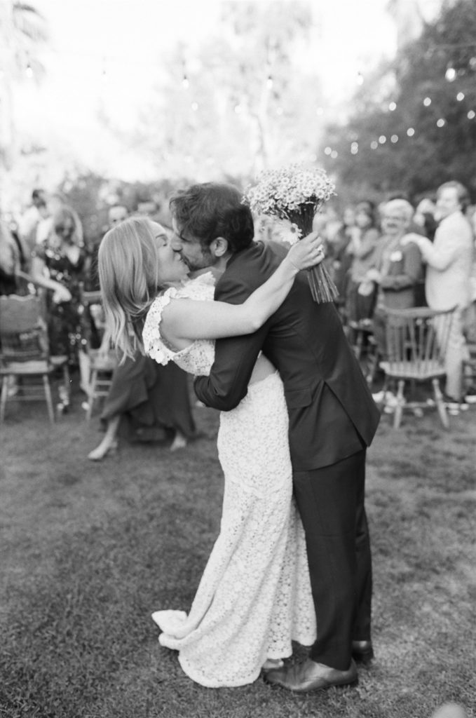 bride and groom kiss at the end of the aisle during wedding ceremony