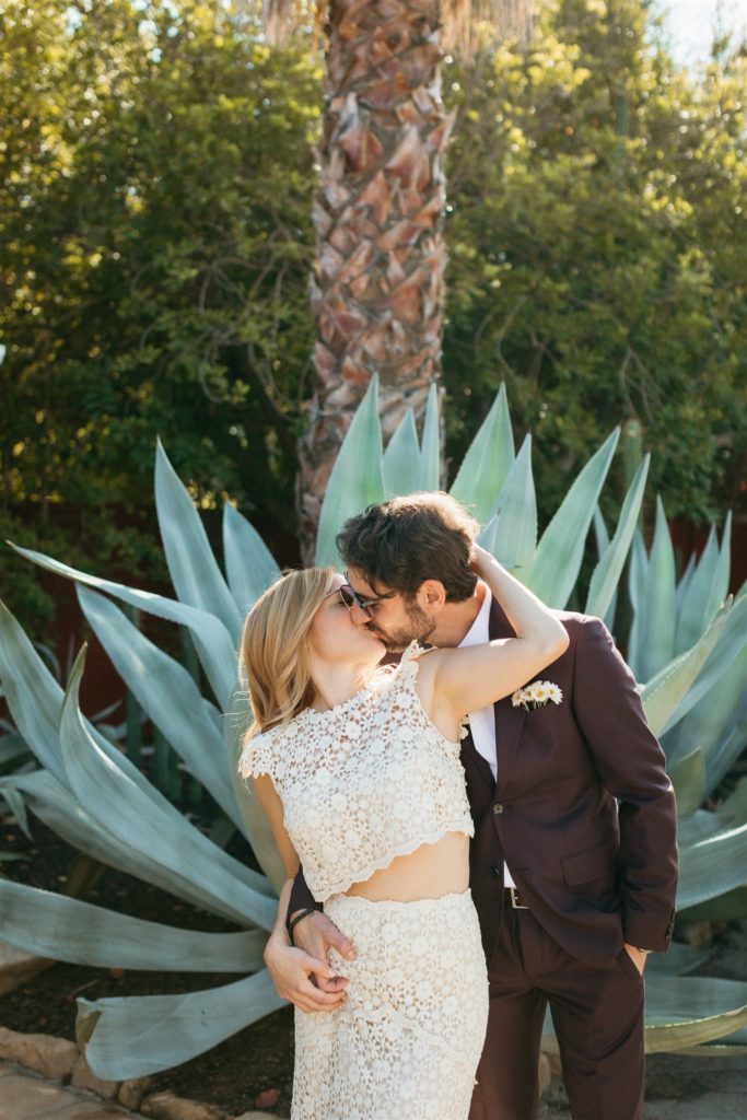bride and groom wearing sunglasses in front of large aloe vera plant