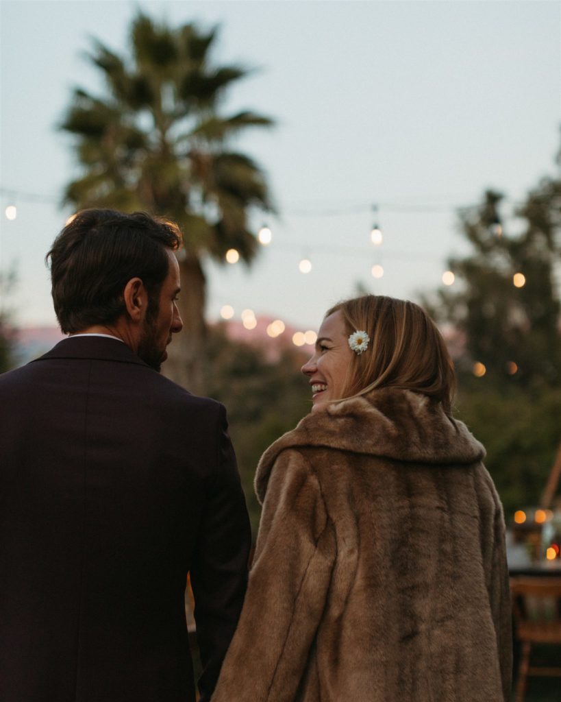 bride in fur coat and groom in maroon suit take portrait shots