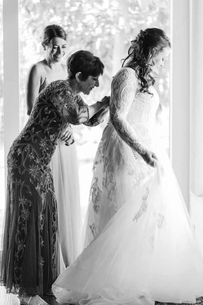bride getting into wedding dress with mother of the bride