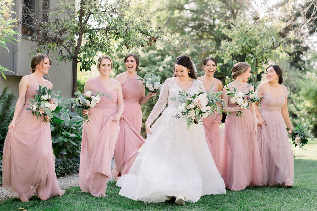 bride in long sleeve wedding dress with bridesmaids in pink bridesmaid dresses