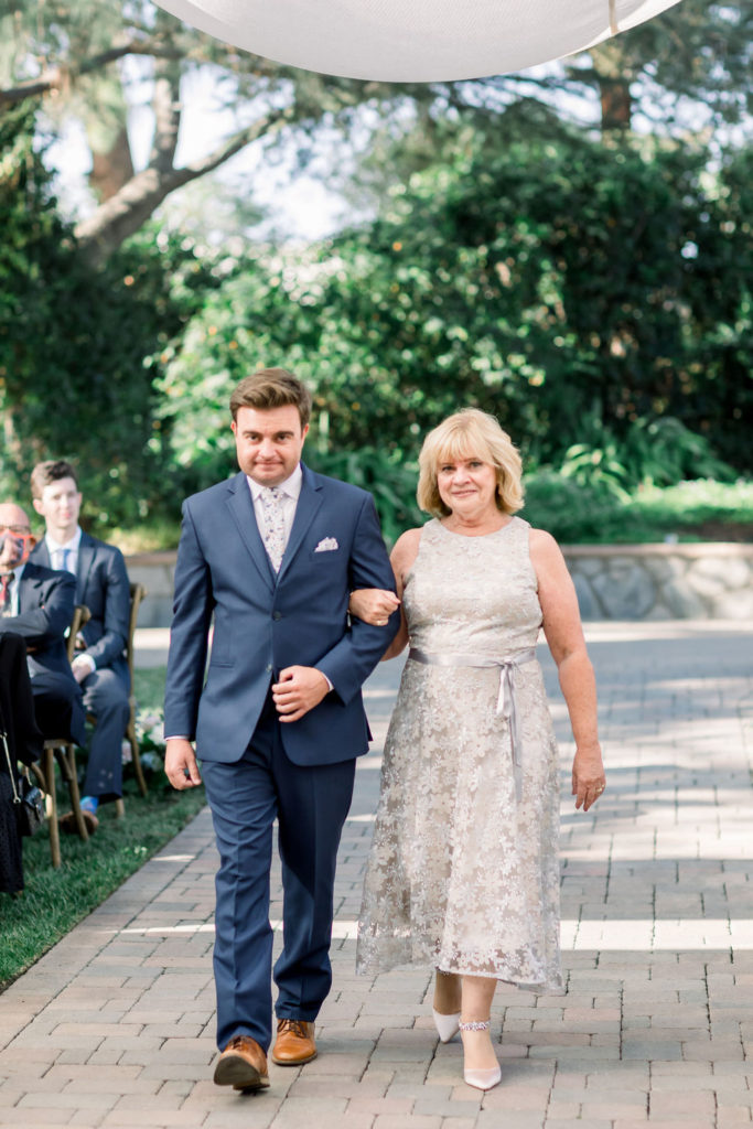 groom walks with mother of groom down aisle