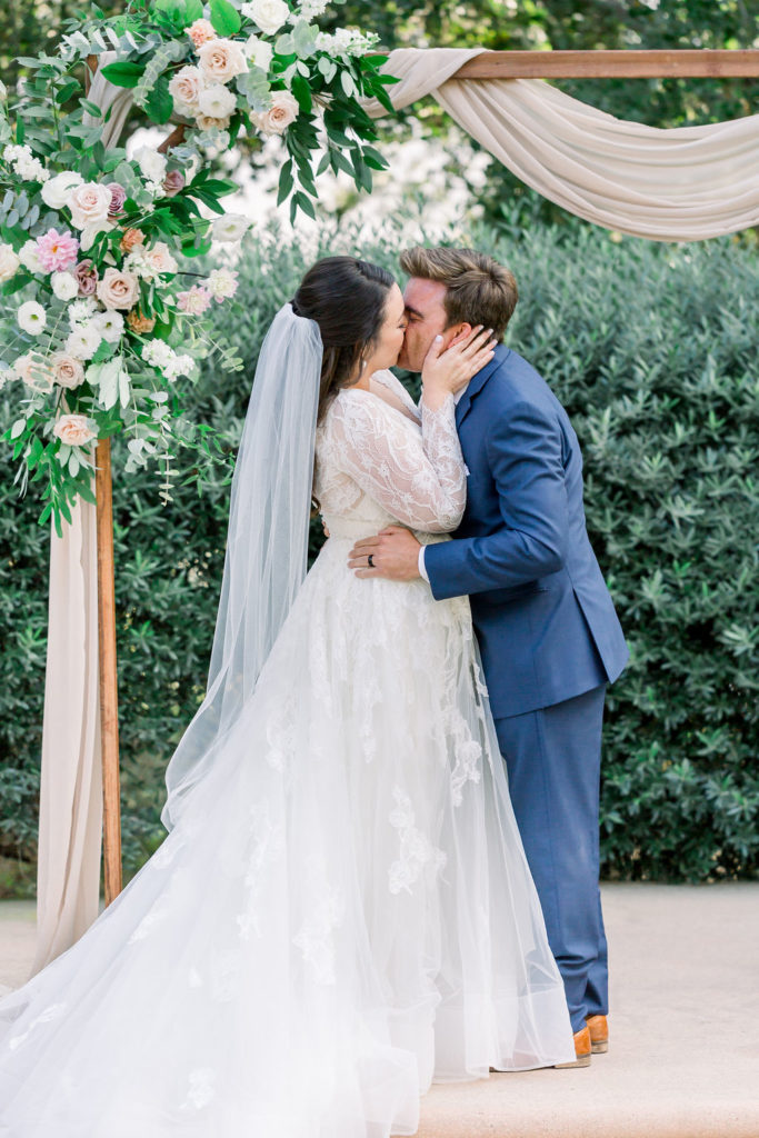 bride and groom first kiss during charming wedding ceremony at Maravilla Gardens