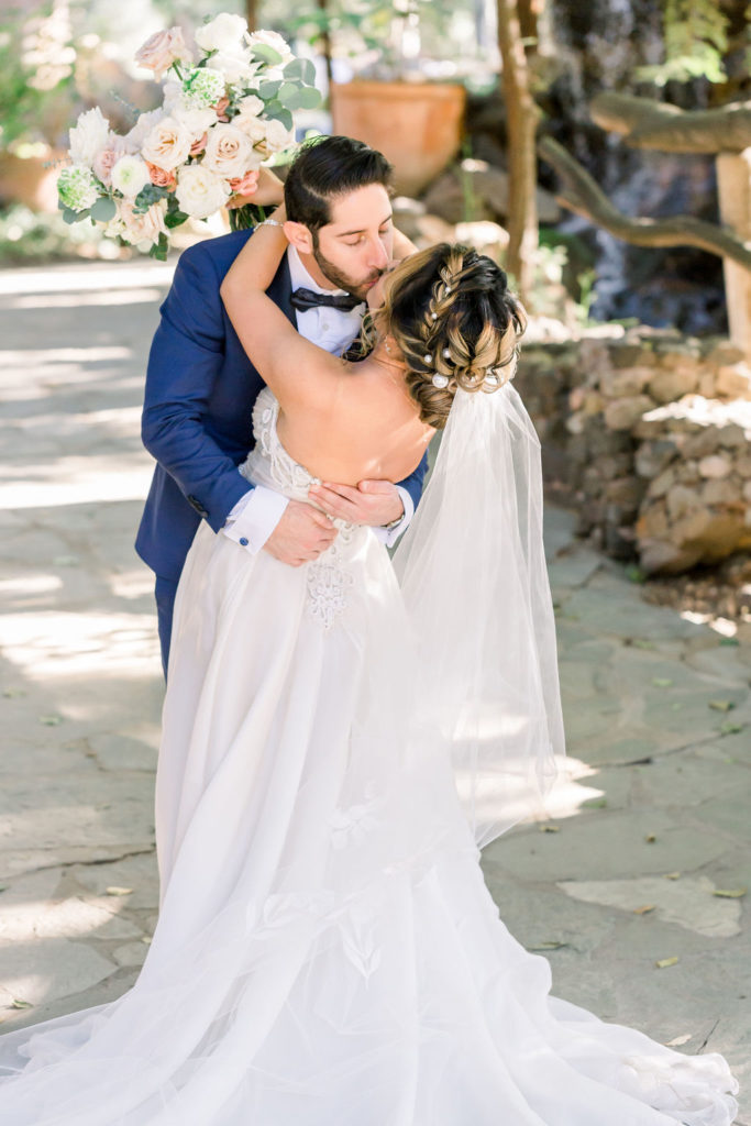 bride wearing beaded sweetheart neckline strapless wedding dress with groom wearing blue suit and black bow tie