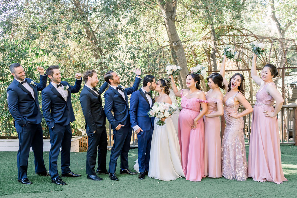 bride and groom take photo with wedding party in pink and blue