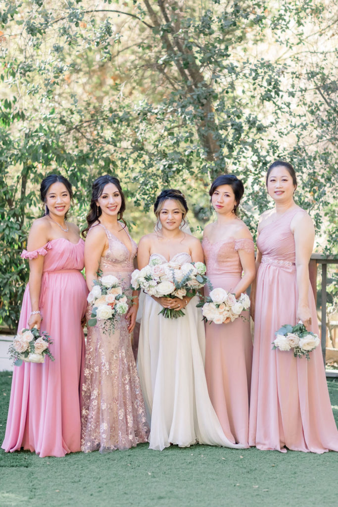bride in beaded strapless wedding dress stands with her bridesmaids in mix matched pink dresses