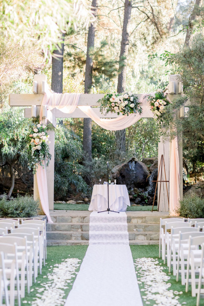 romantic wedding ceremony at Calamigos Ranch with soft pink chiffon draping over arch