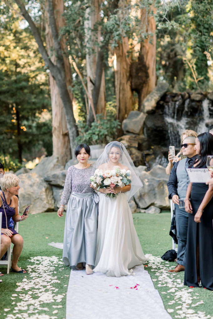 bride walks down aisle with mother during glamorous wedding ceremony at Calamigos Ranch