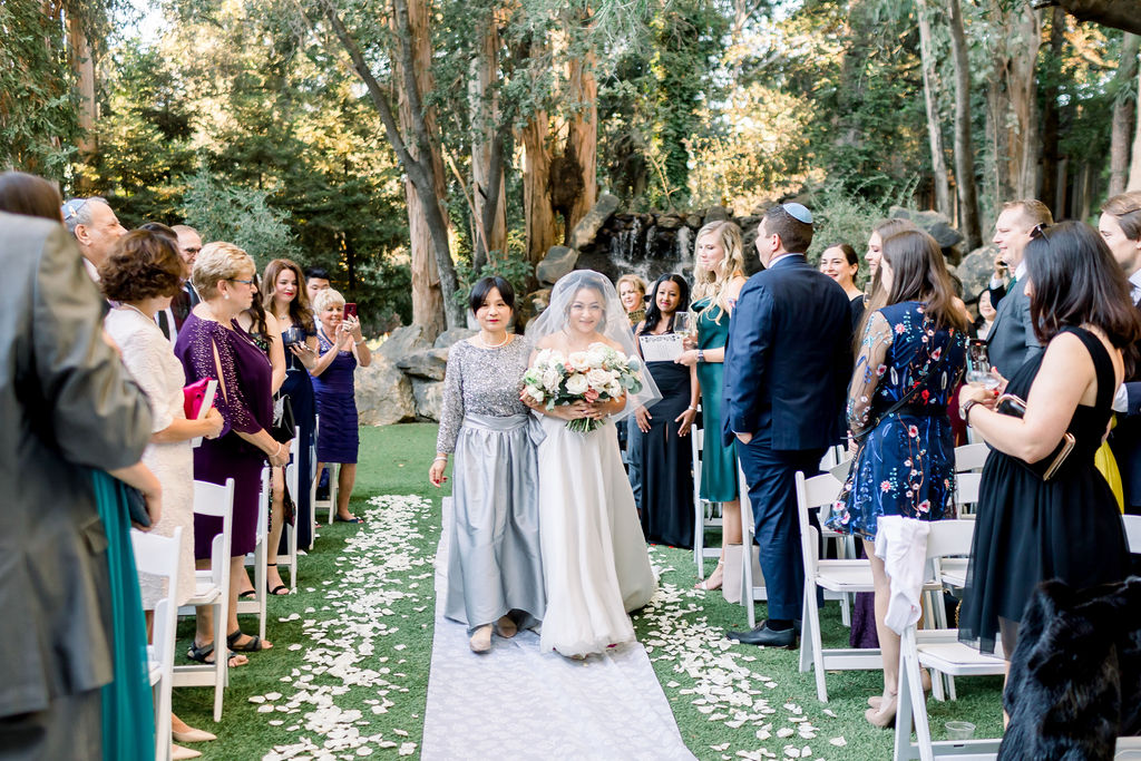 bride walks down aisle with mother during glamorous wedding ceremony at Calamigos Ranch