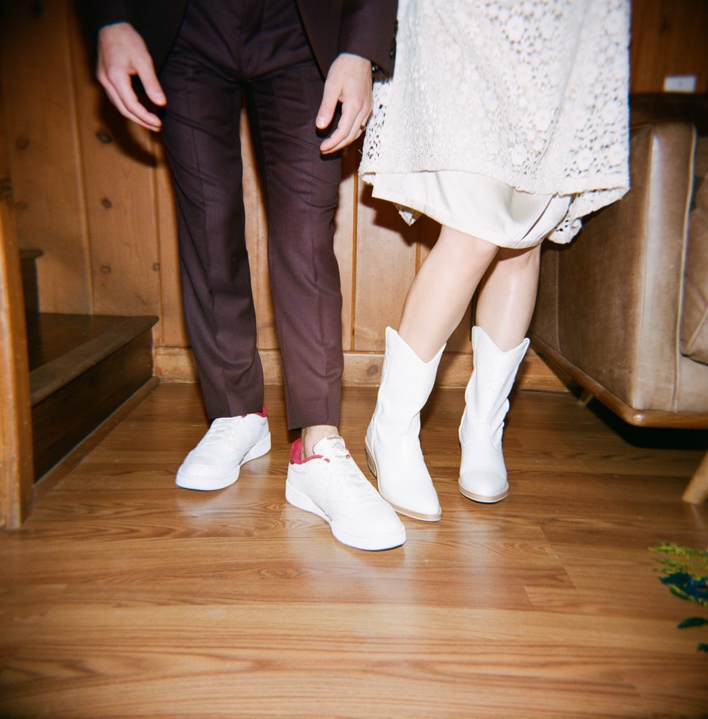 groom changes in casual shoes and bride changes into white cowboy boots after ceremony