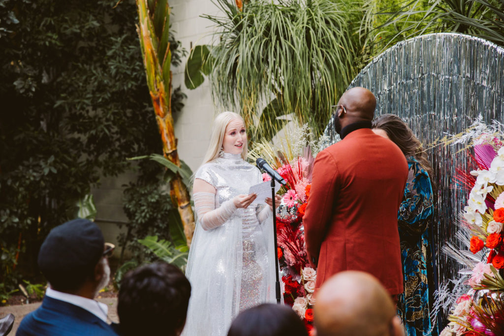 bride in silver wedding dress reads vows during wedding ceremony at Millwick in DTLA