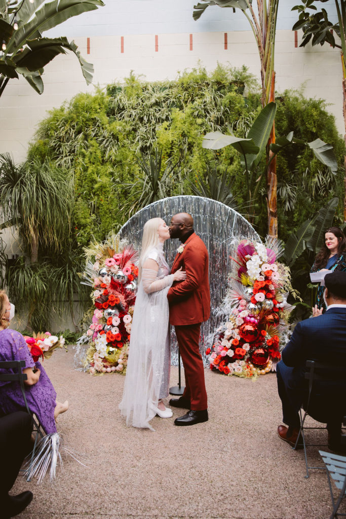 bride and groom first kiss during disco inspired wedding ceremony at Millwick in DTLA
