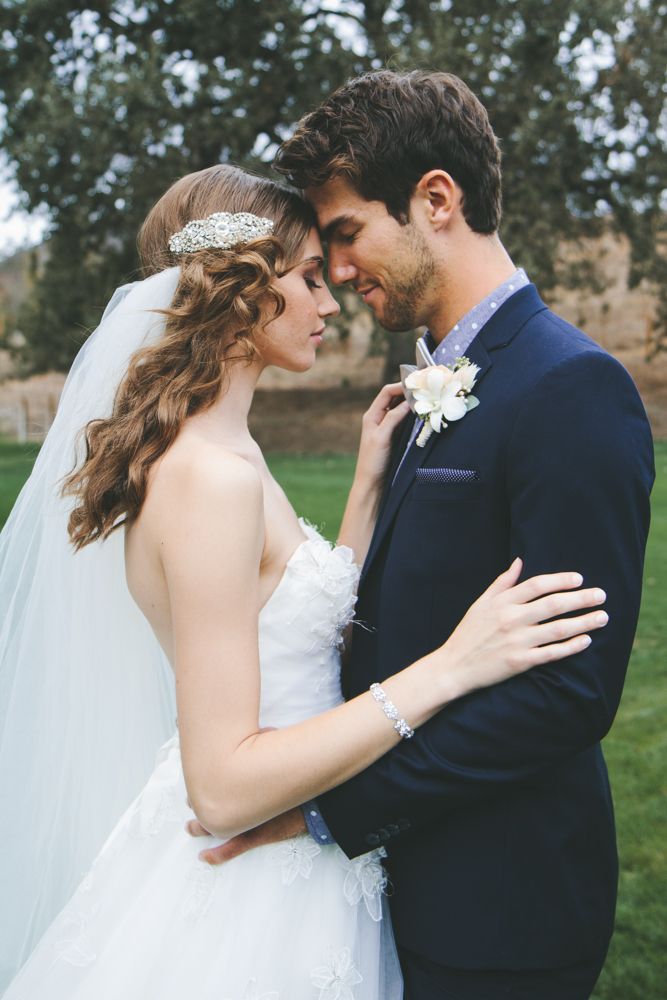 Rustic elegant styled wedding shoot, bridal hair with crystal clip and chapel length gown, groom with navy suit and rose boutonniere