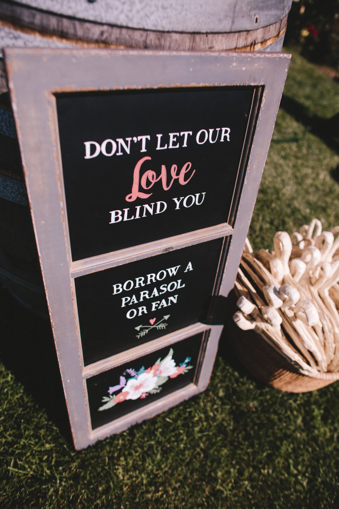 Saddlerock Ranch wedding, parasols and fans for guests with a "don't let our love blind you" sign