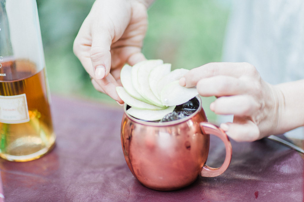 Signature drinks moscow mules in a copper mug with apple slices at Rancho Las Lomas