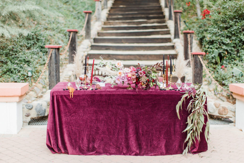 Sweetheart table with La Tavola velvet linens at Rancho Las Lomas purple white and burgundy fall flowers for a wedding