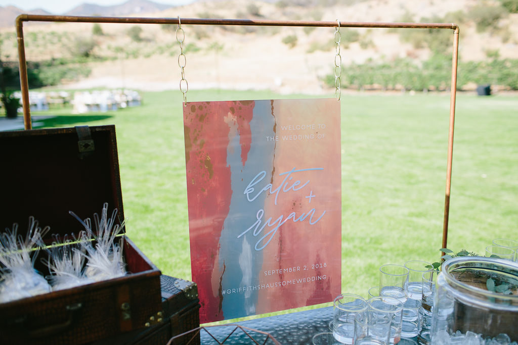 Bright pink orange and blue wedding welcome acrylic sign at Triunfo Creek Vineyards wedding ceremony