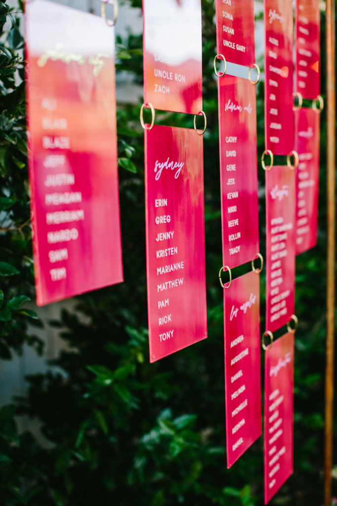 neon pink hanging acrylic seating chart at bright vineyard wedding reception at Triunfo Creek Vineyards