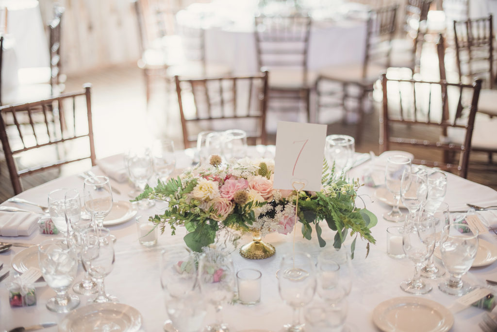 An emotional calamigos ranch wedding, reception tables with pink floral centerpiece and gold table numbers
