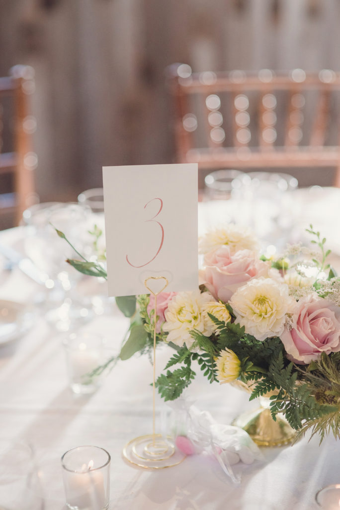An emotional calamigos ranch wedding, reception tables with pink floral centerpiece and gold table numbers