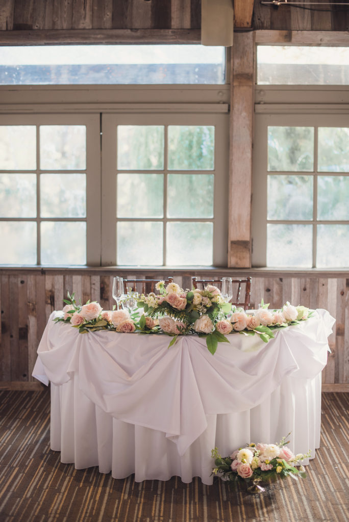An emotional calamigos ranch wedding, reception tables with pink floral centerpiece and gold table numbers, sweetheart table